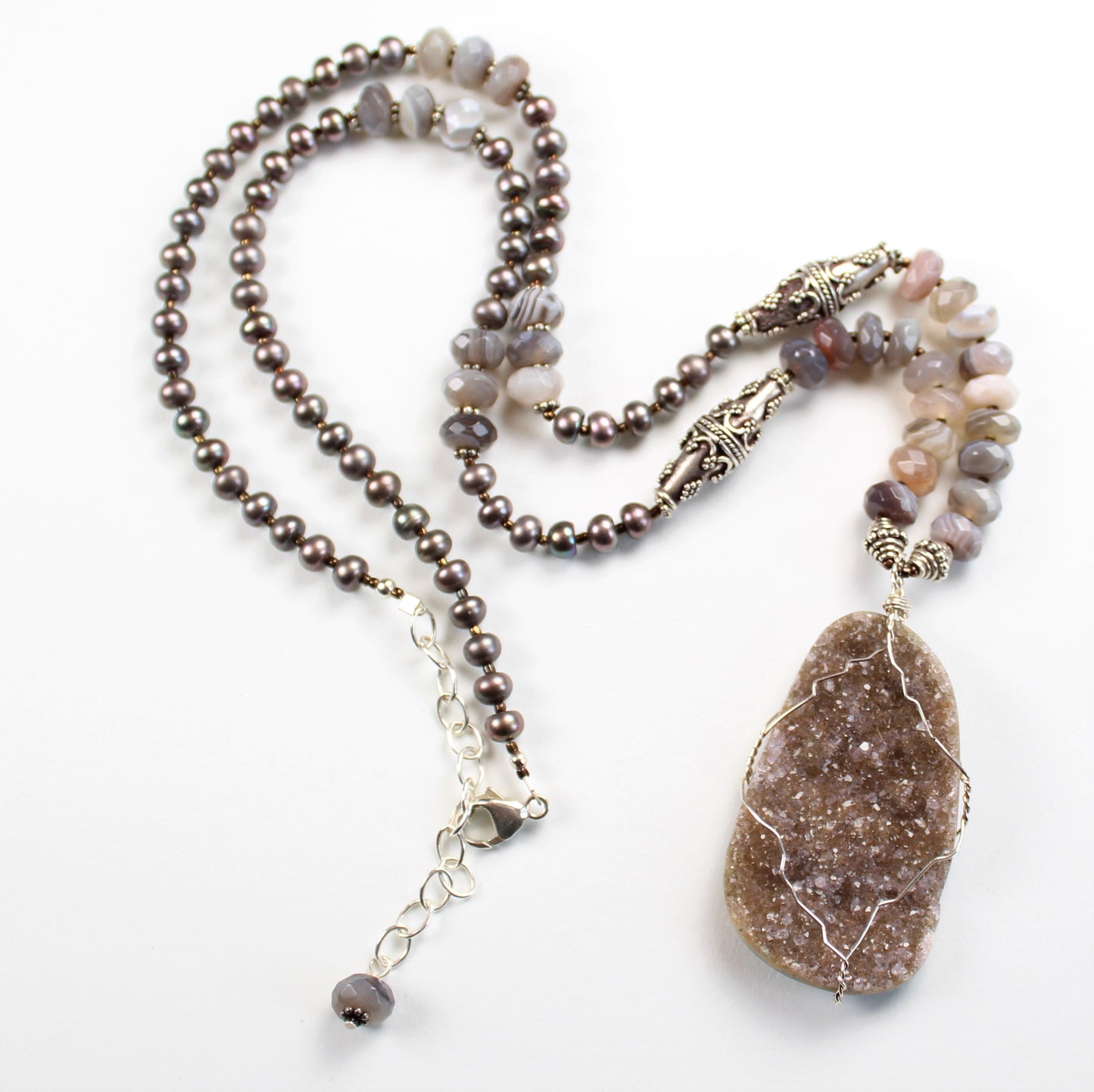 25 inch long mauve pearl and Botswana agate necklace features bali sterling silver beads and a wire wrapped druzy pendant.