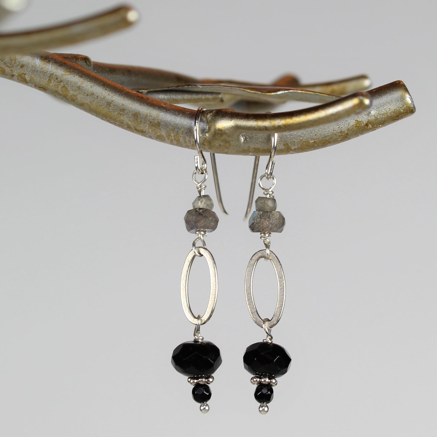 silver wire earrings with black onyx dangle off of brushed silver oval loop and small faceted labradorite