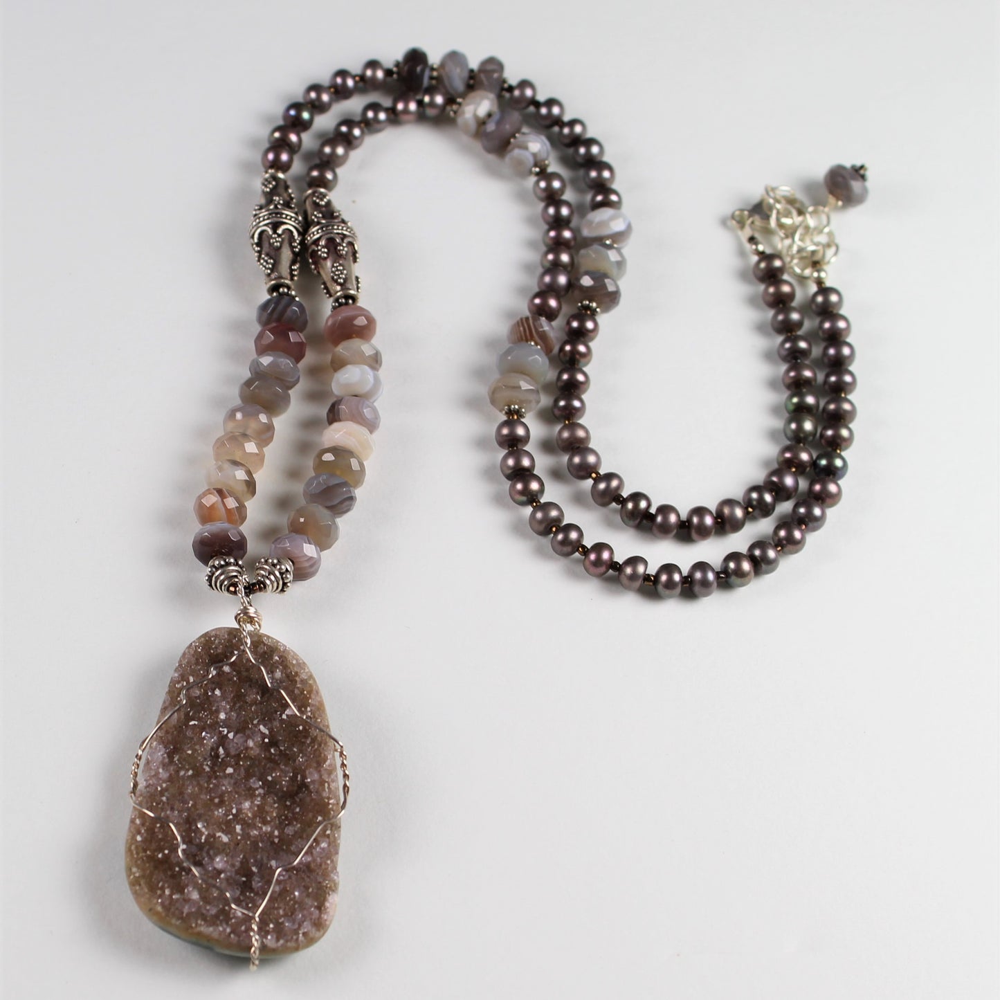 25 inch long mauve pearl and Botswana agate necklace features bali sterling silver beads and a wire wrapped druzy pendant.