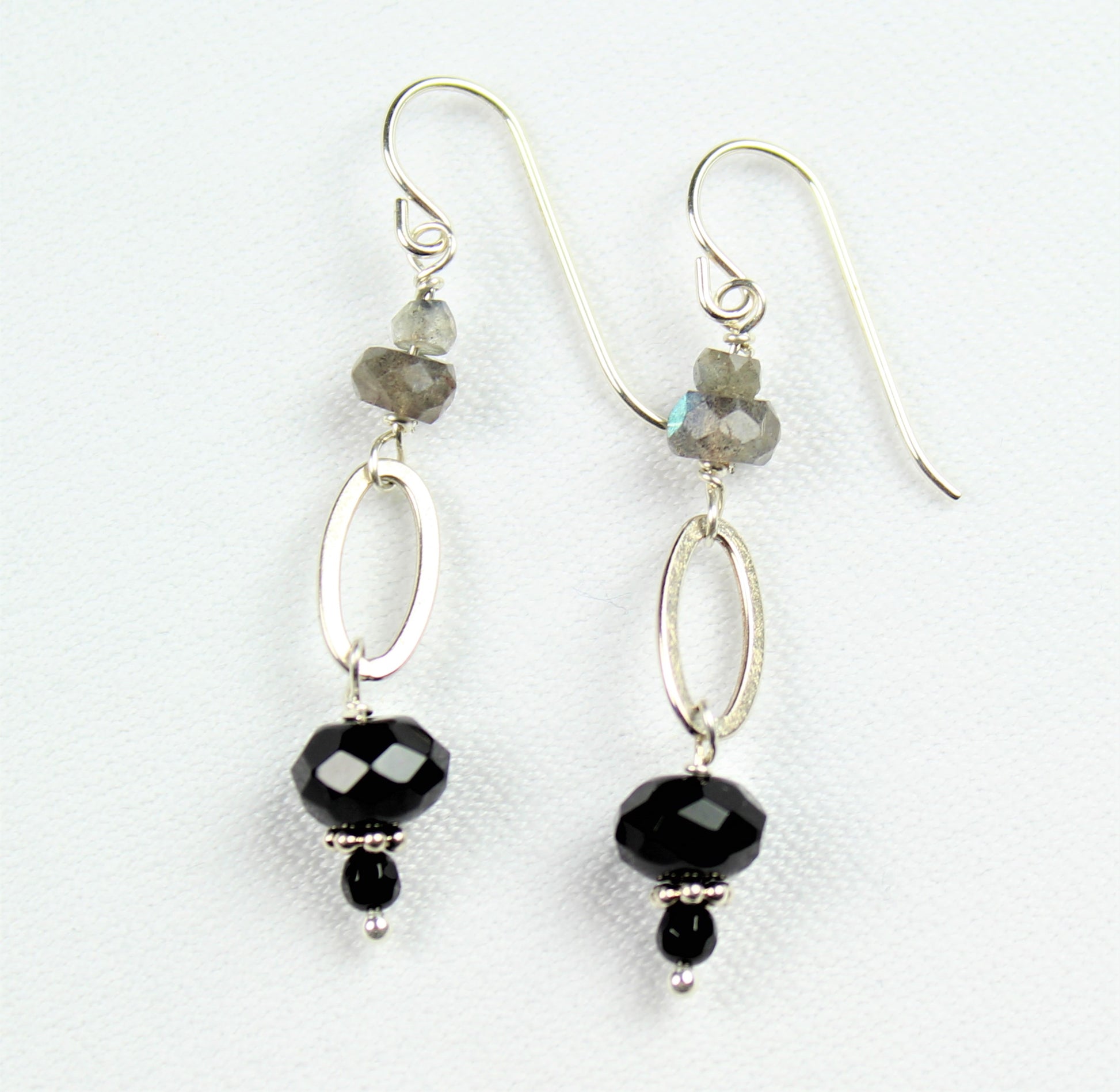 silver wire earrings with black onyx dangle off of brushed silver oval loop and small faceted labradorite