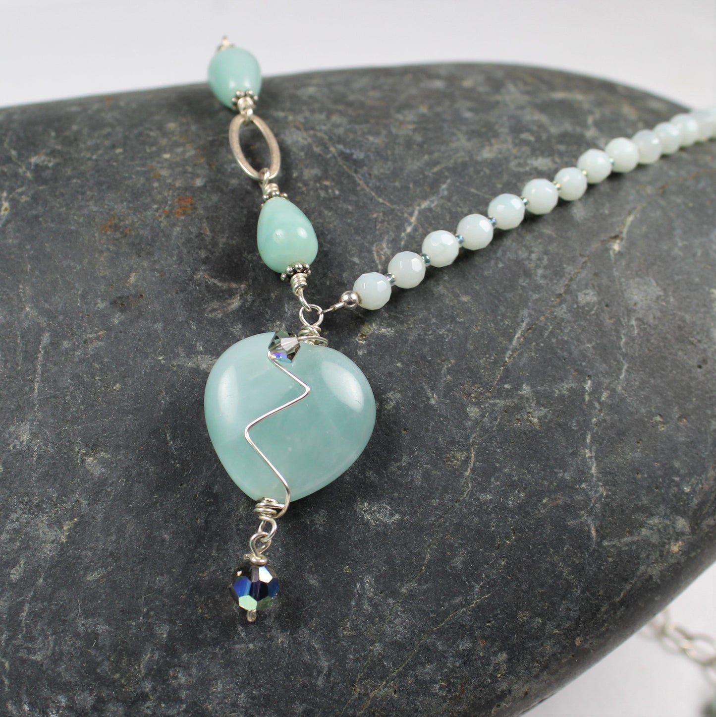 Heart shaped aventurine pendant with sterling wire detail and crystal accents hangs on asymmetrical chain of sterling silver and aventurine beads. 