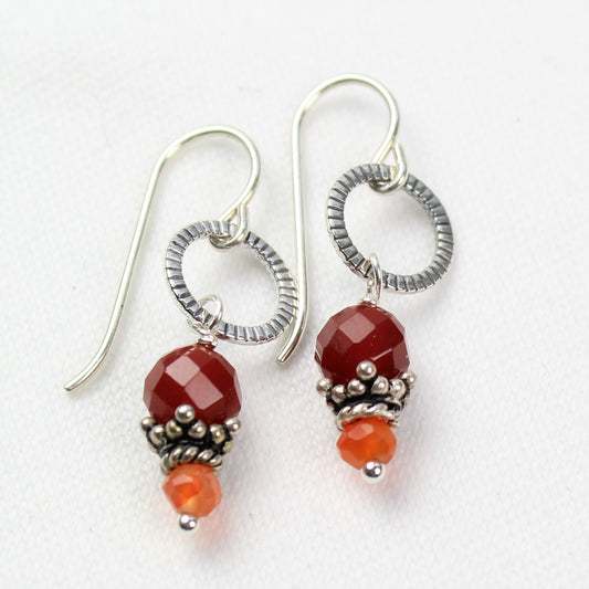 Two tones of faceted Carnelian beads dangle off of antiqued sterling loops.